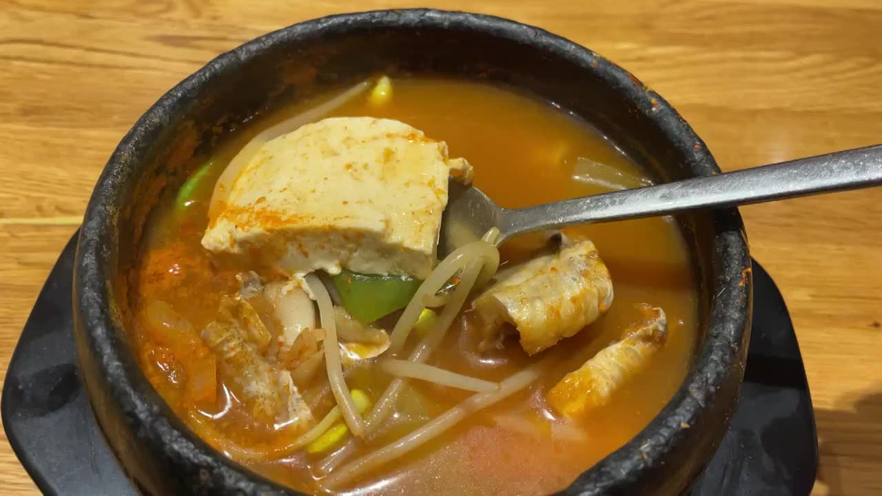 吉林延边 延吉 一家朝鲜族餐馆内售卖的特色热腾腾的明太鱼豆腐汤 辣汤 豆芽 勺子捞起一块豆腐视频素材