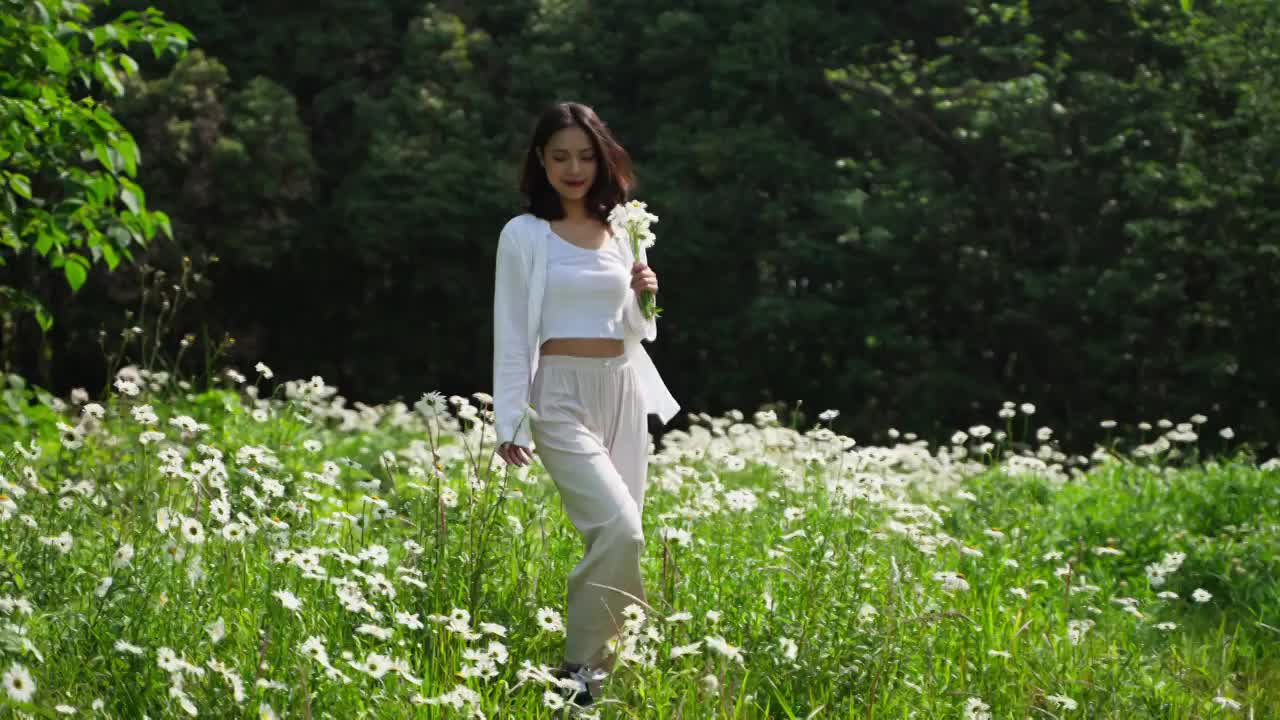 美丽女孩手拿鲜花开心快乐走在春天草地享受自然视频下载
