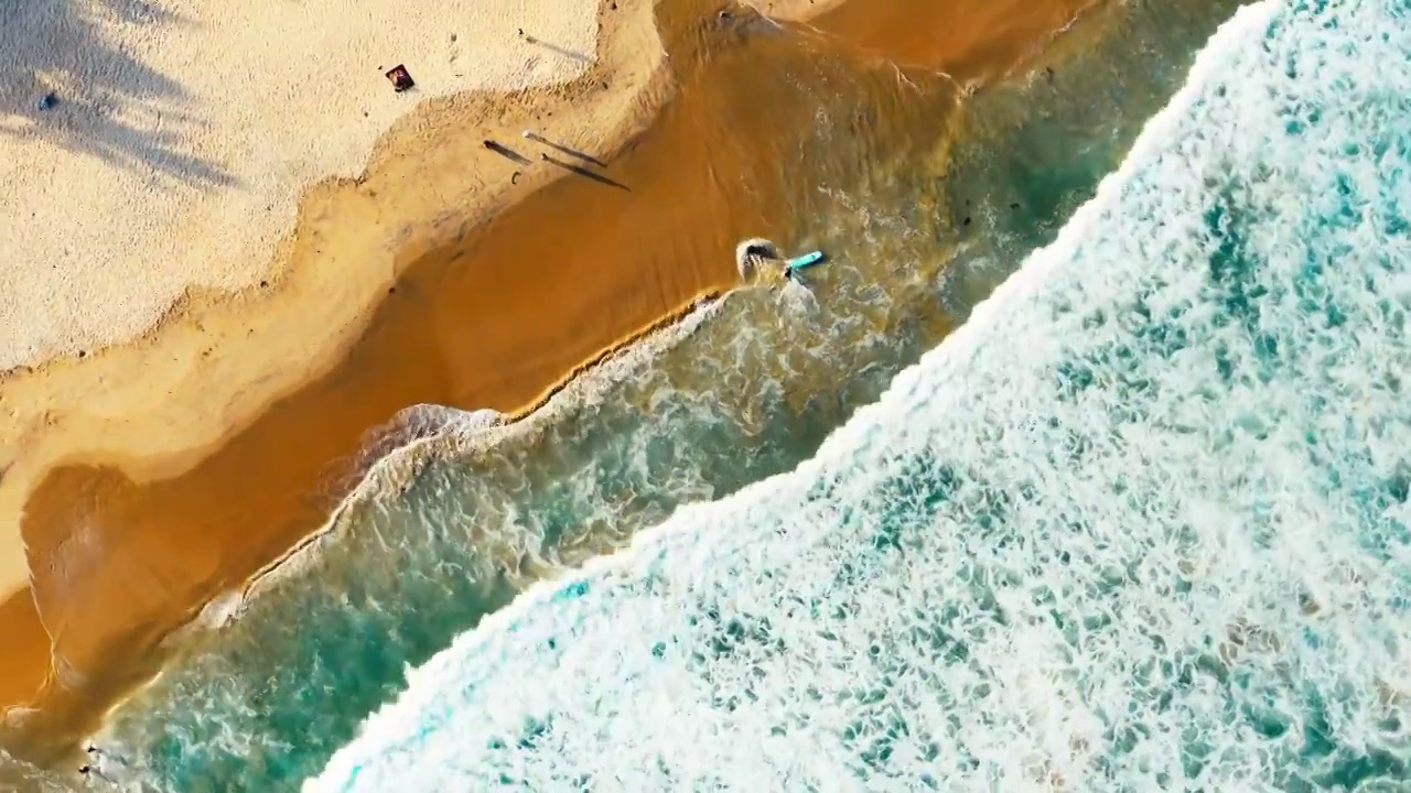 4K航拍海南万宁海滩边手拿冲浪板的运动员视频素材