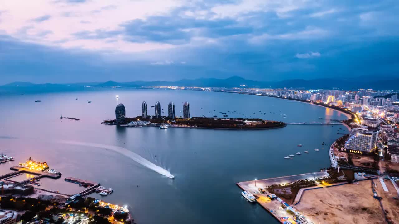 中国海南三亚三亚湾凤凰岛和城市天际线风光夜景航拍延时摄影视频下载
