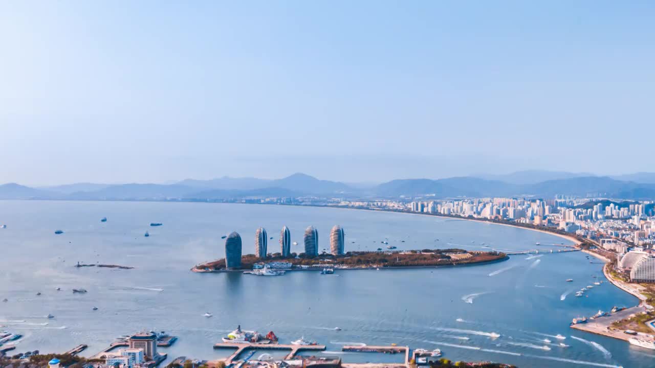 中国海南三亚凤凰岛穿梭的游艇城市天际线延时摄影视频下载