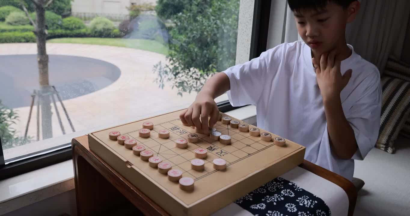 可爱的男孩在窗边下中国象棋视频素材