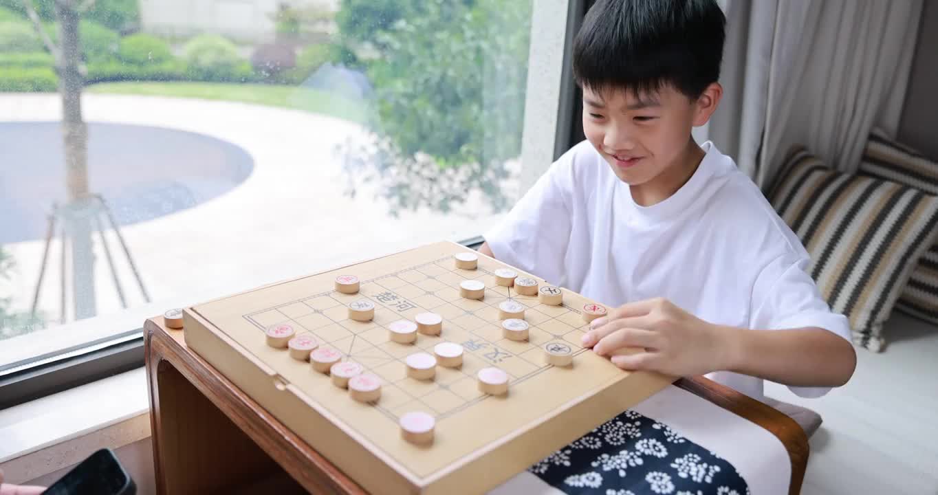 可爱的男孩在窗边下中国象棋视频素材