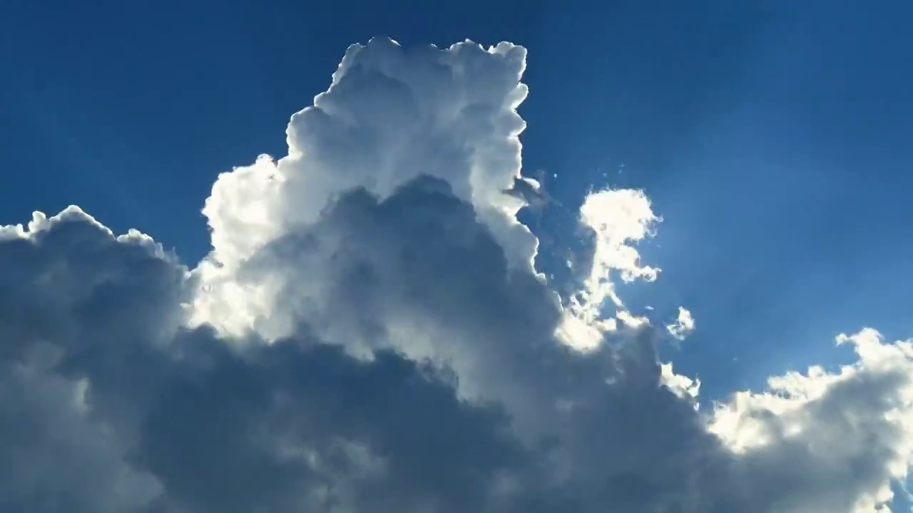 风起云涌的蓝天，光芒四射太阳从云朵中闪亮出现视频下载