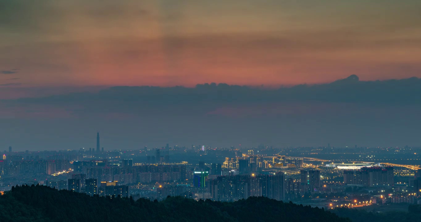 龙泉山上俯瞰雾蒙蒙的成都市区，夕阳西下，日转夜。大运会主体育馆亮起明亮的灯光视频下载
