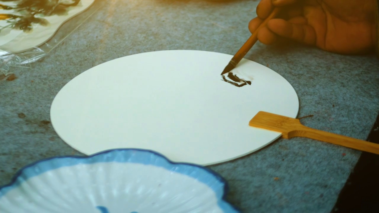 中国传统画师正在用毛笔蘸墨在扇子上绘画制作团扇工艺品非遗传承笔墨文化中国古风元素山水国画扇子工艺品视频下载