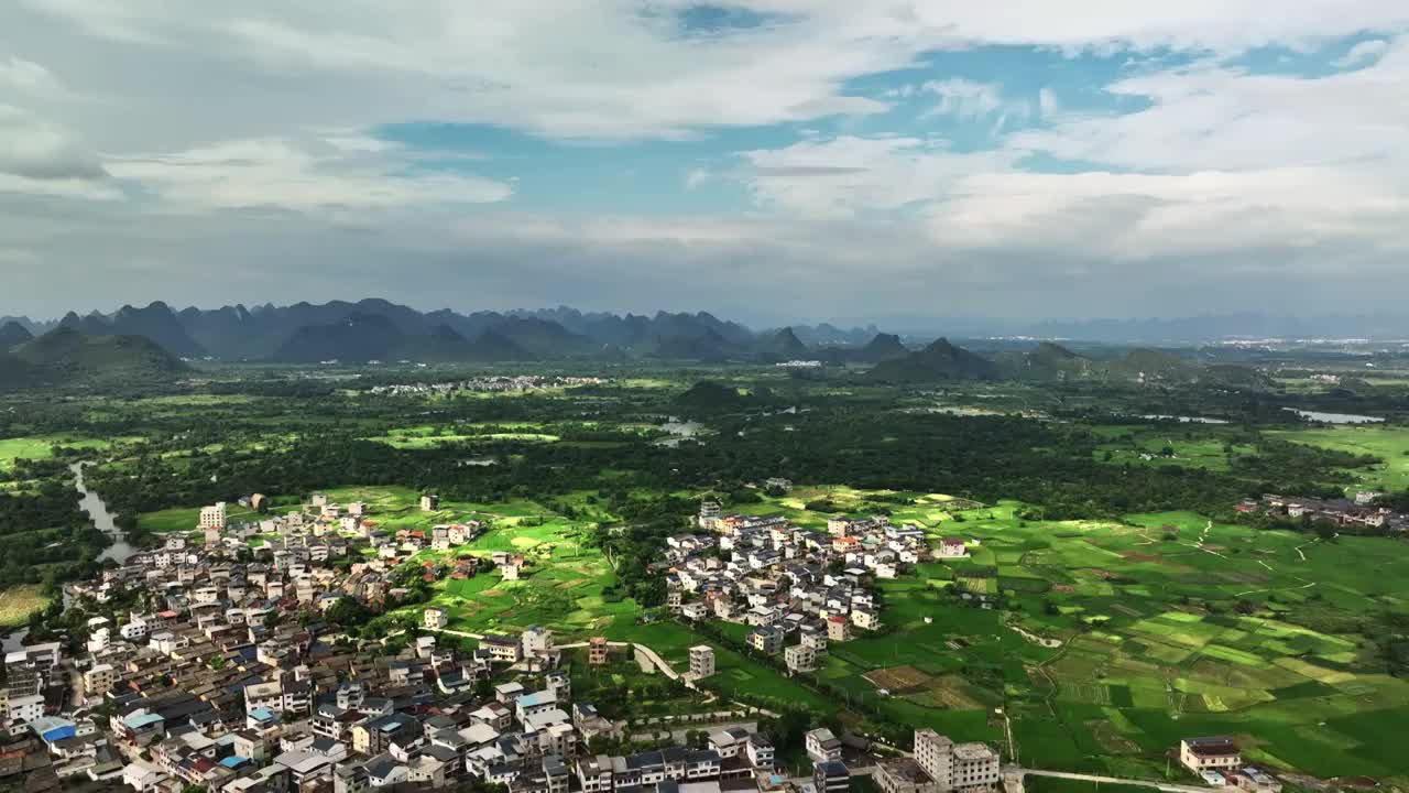 蓝天白云下航拍桂林喀斯特地貌山峰间的村庄和绿色稻田视频下载