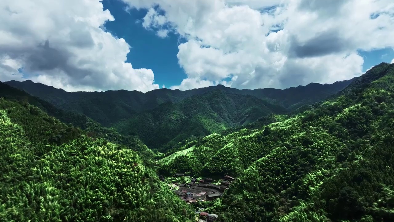 航拍蓝天白云阳光下桂林山区绿色的山脉和山谷中的少数民族村寨视频下载