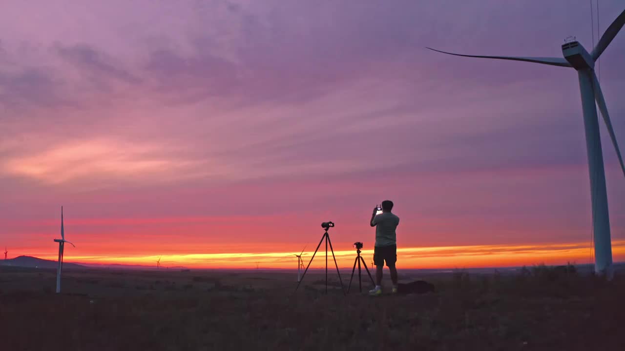 夕阳美景下航拍摄影师自拍和风力发电机合影视频下载
