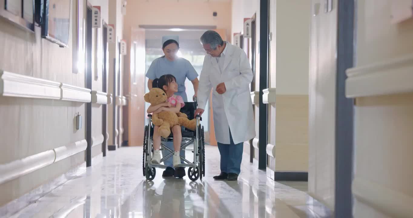 走廊内医护人员推着坐轮椅的小女孩视频下载