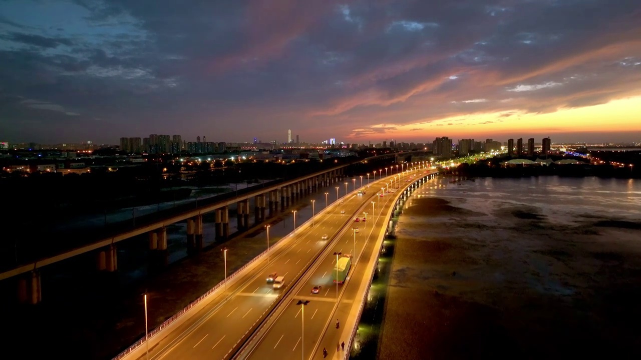 傍晚时分晚霞里的苏州阳澄湖上高铁与车流风景航拍视频下载
