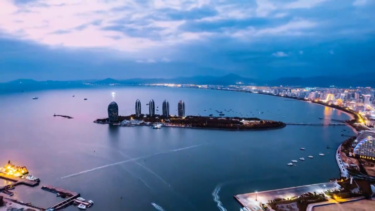 中国海南三亚三亚湾凤凰岛和城市天际线风光夜景航拍延时摄影视频下载