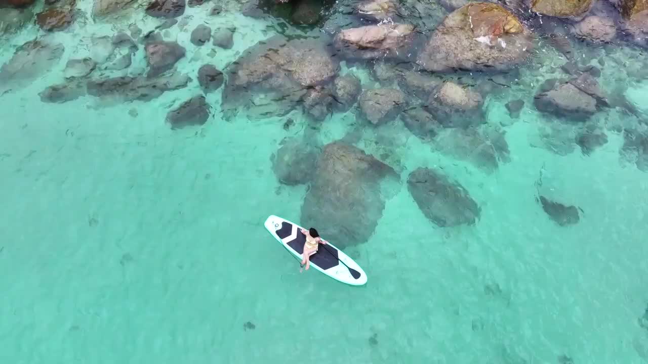 碧水浅滩处玩浆板的女子视频素材