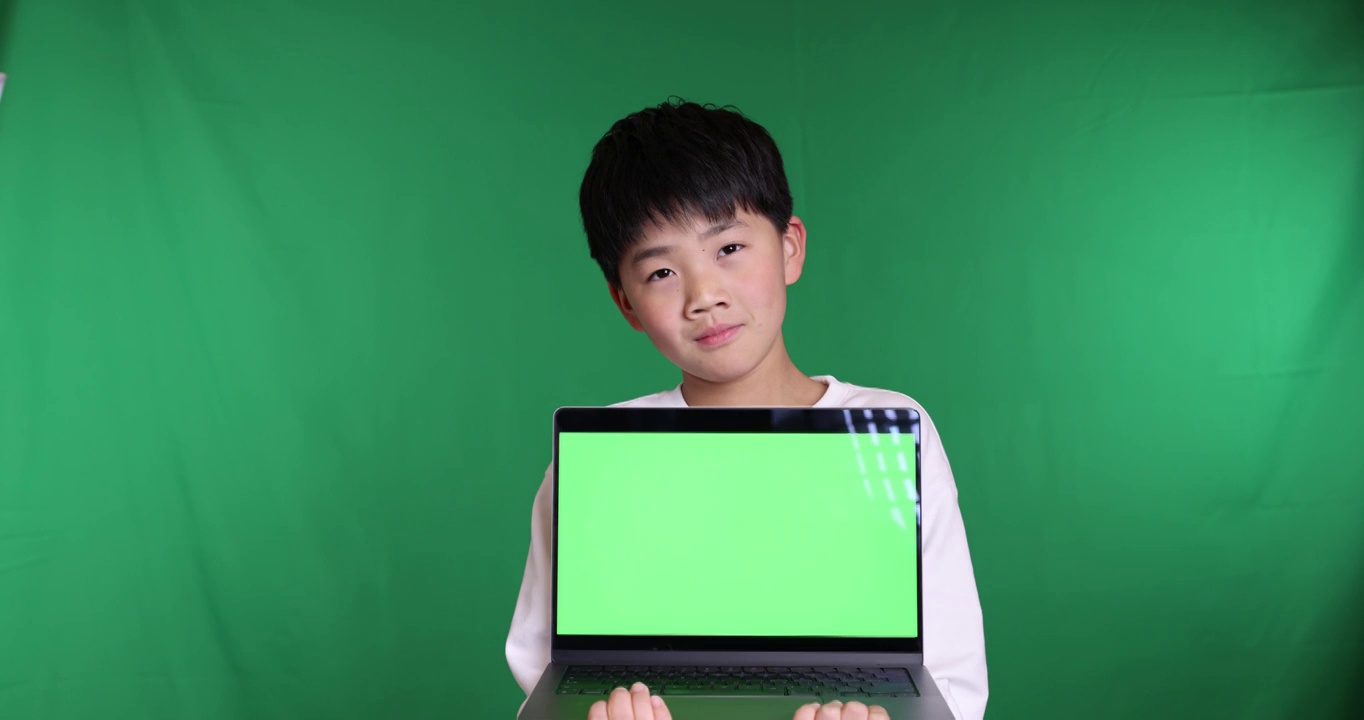 可爱的中国小男孩展示绿屏笔记本电脑视频素材