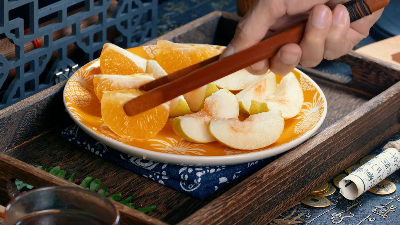 中式古风场景里水果被切开准备食用，有柑橘和梨子鲜甜多汁味道鲜美新鲜现切的果盘配上国风茶饮健康瘦身套餐视频下载