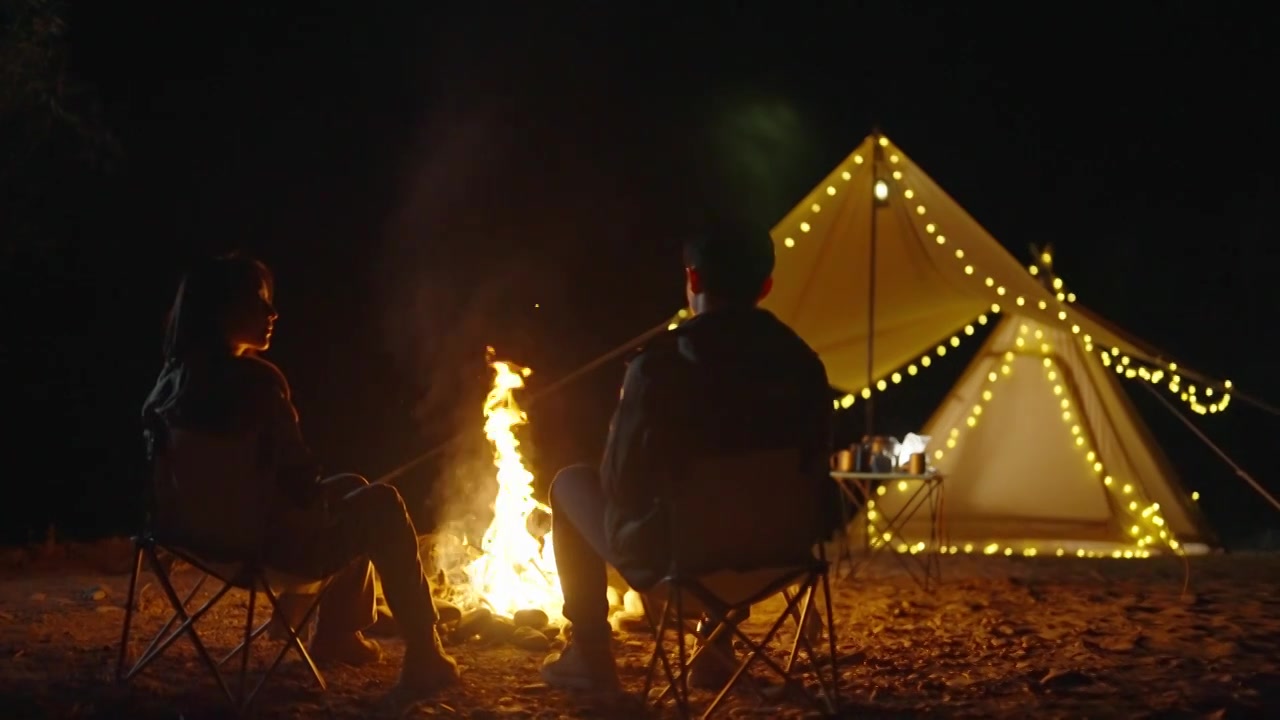 年轻情侣晚上在户外露营烤火视频素材