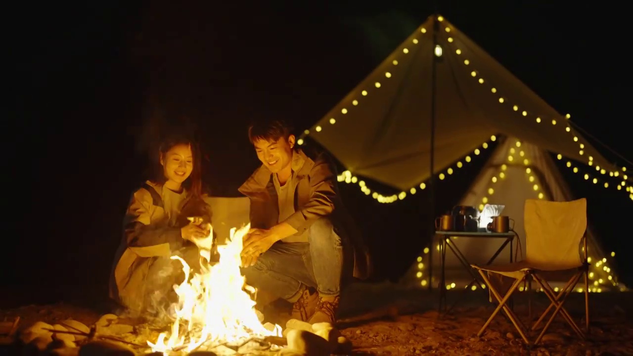 年轻情侣晚上在户外露营烤火视频素材
