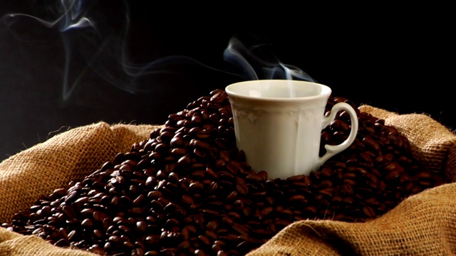 一袋咖啡豆和一杯热气腾腾的咖啡视频素材