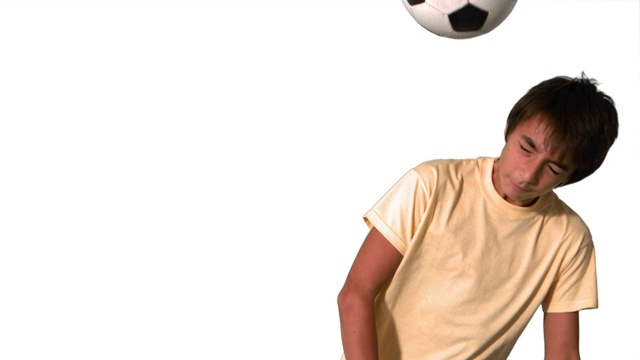 一个外国男孩头顶足球慢动作，在白色背景下视频素材