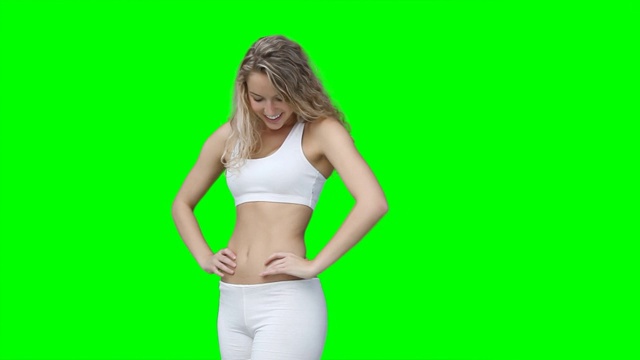 一个穿着训练服的女人在绿色背景下摆姿势视频下载