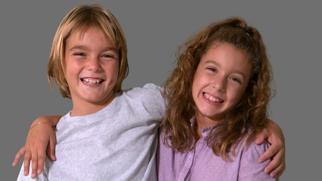 兄弟姐妹在灰色背景的慢镜头中微笑视频下载
