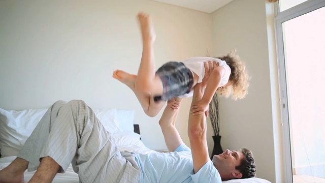 一个躺在床上的男人把他的儿子举到空中视频素材