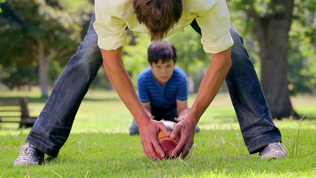 微笑的男人和他的儿子在乡下玩橄榄球视频素材