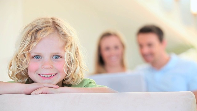 微笑的男孩靠在沙发上，他快乐的父母在后面视频素材