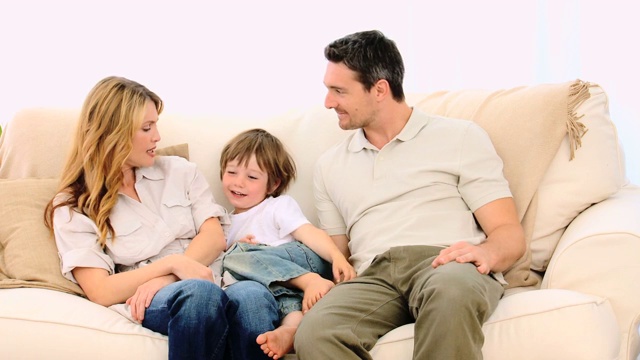 小男孩和他的父母在沙发上聊天视频素材