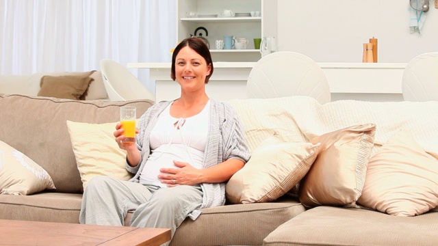 一个孕妇坐在沙发上喝着橙汁视频下载