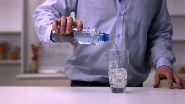 一名男子将水倒入玻璃杯中的慢动作视频下载