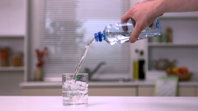 用手将水倒入玻璃杯中的慢动作视频下载