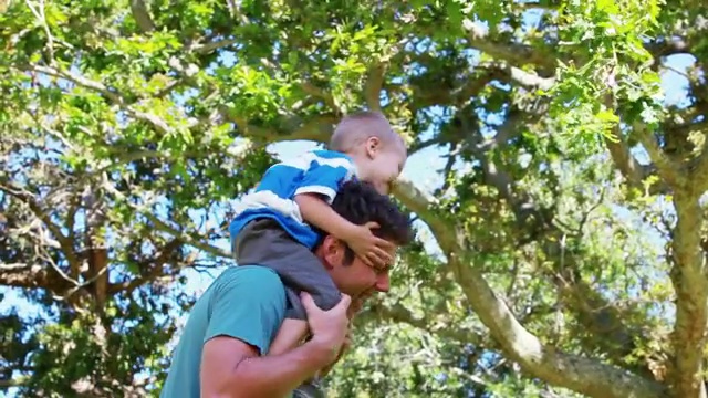 一个男人在公园里把儿子扛在肩上视频素材