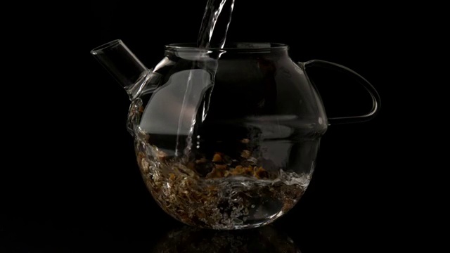 慢动作将水倒入玻璃茶壶，浇在松散的凉茶上视频下载