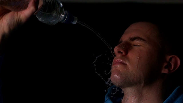 一个年轻人用慢动作把瓶子里的水倒在脸上视频下载