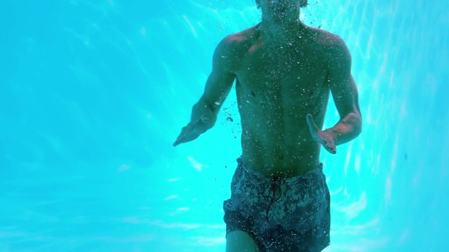快乐的人在游泳池水下摆pose的慢动作视频素材