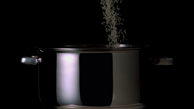米饭倒入锅中的慢镜头，背景为黑色视频素材
