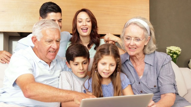 快乐的大家庭在客厅的沙发上一起使用笔记本电脑视频素材