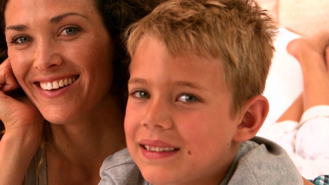 母亲和儿子躺在床上对着慢镜头微笑视频素材