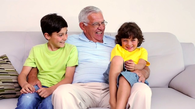 老人和他的孙子坐在客厅的沙发上视频素材