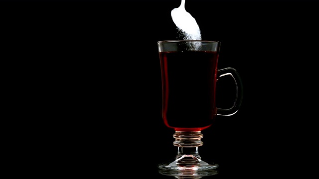 慢动作将糖倒入玻璃杯中的茶中视频素材