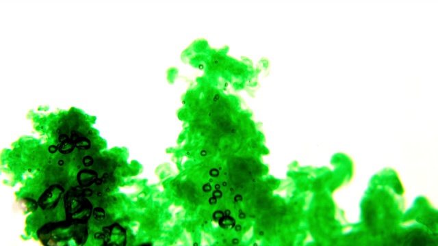 在慢镜头中，绿色墨水在白色背景上倒入水中视频素材