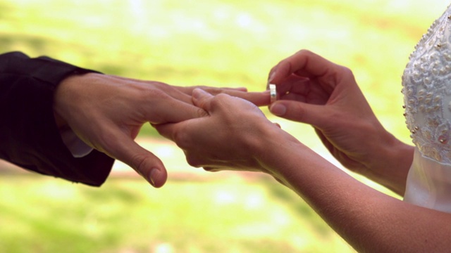 在慢镜头中，女子将戒指戴在新郎的手指上视频下载