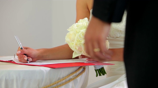 新娘在新郎的注视下签署结婚登记簿视频下载