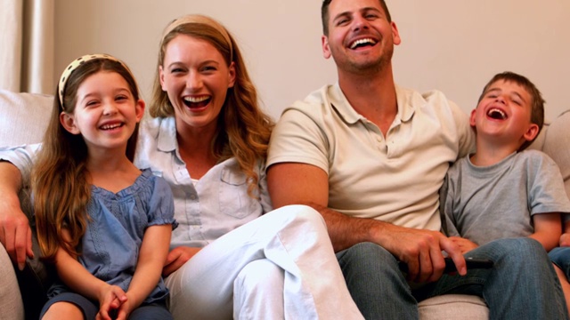 快乐的年轻家庭在沙发上笑的慢镜头视频素材