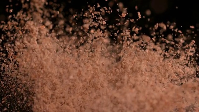 在慢镜头中，棕色面粉在黑色背景下弹跳视频素材