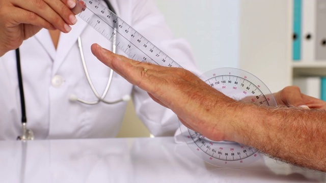 医生在医院办公室用测角仪测量病人的手腕视频下载