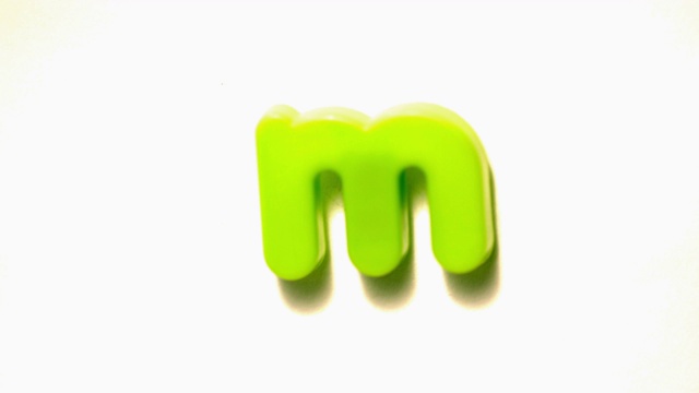 慢镜头中，绿色字母m脱离白色背景视频素材