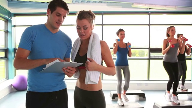 在健身房有氧运动课上和教练交谈的女人视频下载