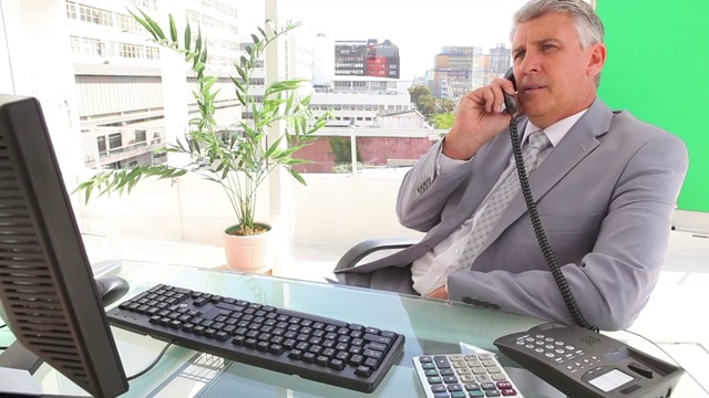 严肃的生意人在办公室打电话前打字视频素材